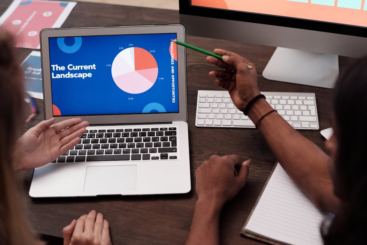 gallery-03 Team discussing data with graph on laptop screen in office setting.